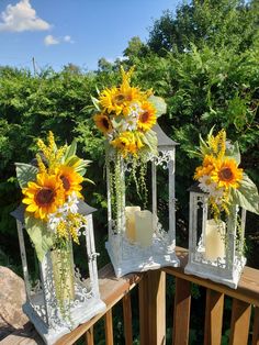 three white lanterns with sunflowers and candles