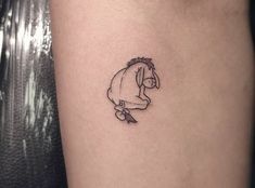 a small black and white tattoo of a horse on the right thigh, with a person's head in the background