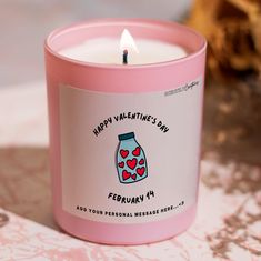 a pink candle is sitting on a table with a message written in the jar and heart - shaped candles