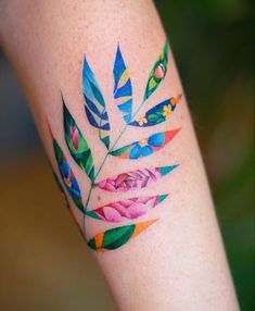 a colorful tattoo on the leg of a woman with flowers and leaves painted on it