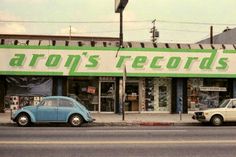 an old car parked in front of a record store