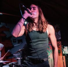 a man with long hair singing into a microphone