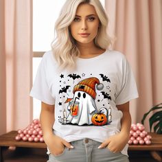 a woman wearing a white t - shirt with a ghost and pumpkin on it