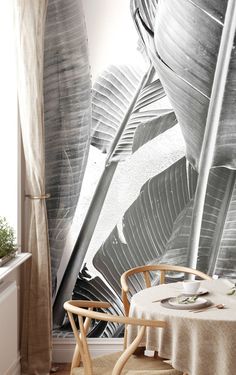 a dining room with a table and chairs in front of a wall mural that has leaves on it