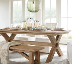 a dining room table and bench in front of large windows