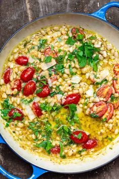 a pan filled with corn and tomatoes on top of a wooden table