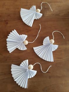 three white paper fan shaped ornaments on a wooden table with string attached to the sides