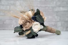 a bridal bouquet with flowers and wheat stalks on a marble tableclothed surface