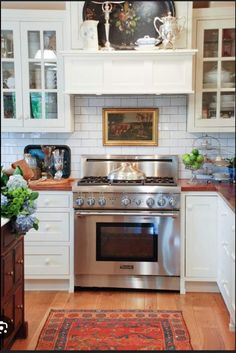 a stove top oven sitting inside of a kitchen next to white cabinets and wooden floors