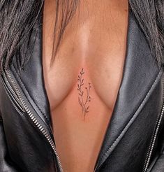 a woman's chest with a small flower tattoo on the left side of her breast