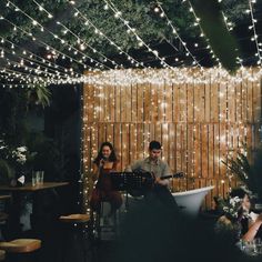 a man and woman playing instruments in front of a tub with lights on the wall