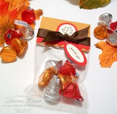 candy wrapped in cellophane and tied with a brown ribbon, sits on a table surrounded by autumn leaves