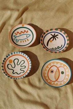 four plates with designs on them sitting on a bed