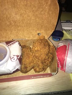 an open take out box with fried chicken and dipping sauce in it on a table