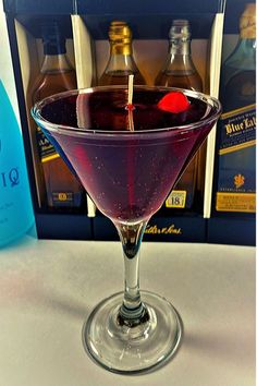 a glass filled with liquid sitting on top of a table next to bottles of alcohol