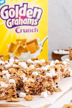 a box of golden graham's crunch next to some cereal and marshmallows