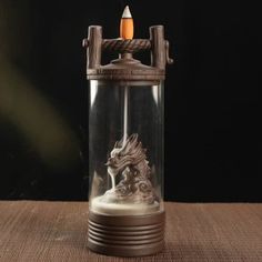 a candle that is inside of a glass container with a dragon on it's side