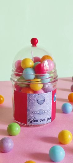 a jar filled with lots of colorful candies on top of a pink tablecloth