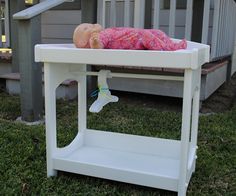 a baby doll laying on top of a white table next to a stair case in front of a house