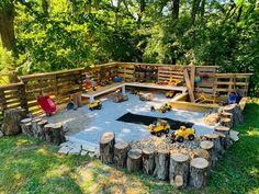 an outdoor play area made out of wood and logs with toys on the ground in it