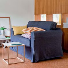 a living room with a blue couch and two side tables on the floor next to it