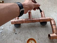 a person is holding a coffee cup and some pipes on the ground with their hands