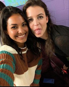 two women taking a selfie in front of a purple wall