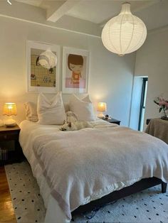 a white bed sitting in a bedroom next to two lamps on either side of the bed