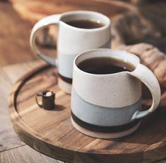 two cups of coffee sitting on top of a wooden tray