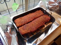 two large meats are cooking in a pan on tin foil next to a window