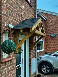 a car is parked in front of a brick building with a wooden porch and roof