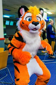 an orange and white tiger mascot standing on its hind legs in the middle of a room