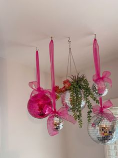 three disco balls hanging from the ceiling with pink ribbons and bows on them in front of a mirror ball chandelier