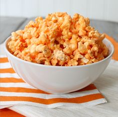 orange creamsice popcorn in a white bowl on an orange and white tablecloth