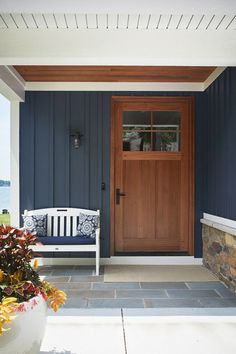 a wooden door sitting next to a white bench on top of a stone floored patio