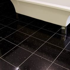 a white bath tub sitting on top of a black tiled floor