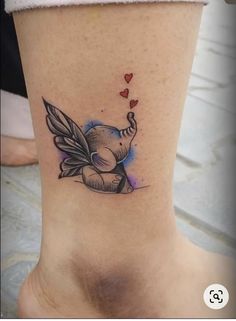 an elephant tattoo on the ankle with hearts coming out of its trunk and wings above it