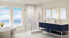 a bathroom with a tub, sink, and large window overlooking the ocean is shown