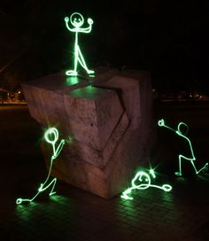 some green lights that are on top of a stone block in the dark with small figures