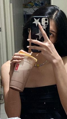 a woman taking a selfie in the mirror with her cell phone and coffee cup