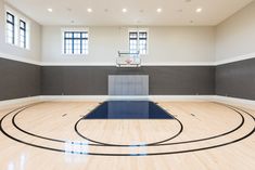 an empty basketball court in a large room with hardwood flooring and windows on the wall