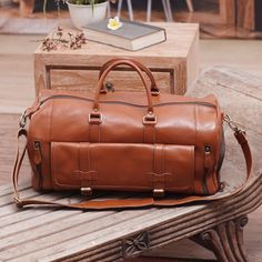 a brown leather bag sitting on top of a wooden bench