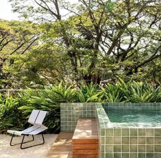 an outdoor swimming pool surrounded by greenery and trees with a lounge chair in the foreground