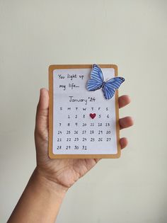 a hand holding a calendar with a blue butterfly on it