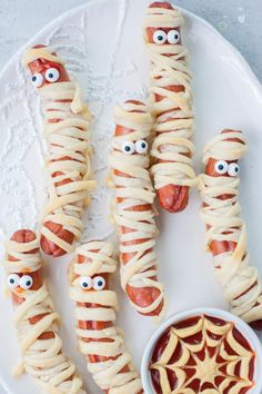 hot dogs wrapped in whip cream with eyes and spider webs on them, ready to be eaten