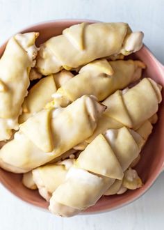 a pink bowl filled with dumplings on top of a white table