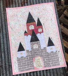 a quilted wall hanging on the side of a metal structure that has a castle in it