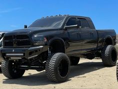 a large black truck parked on top of a dirt field