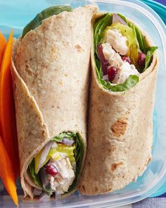 two wraps with chicken salad and carrots in a plastic container on a blue surface