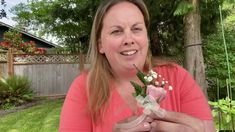 a woman holding a bouquet of flowers in front of her face and smiling at the camera